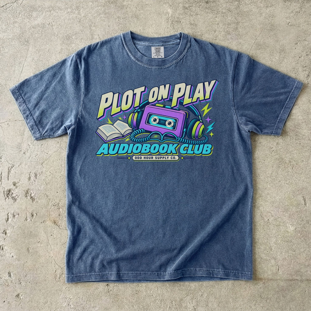 T-Shirt in Denim mit violetter Kassette, Kopfhörern und PLOT ON PLAY AUDIOBOOK CLUB von Odd Hour Supply Co.
