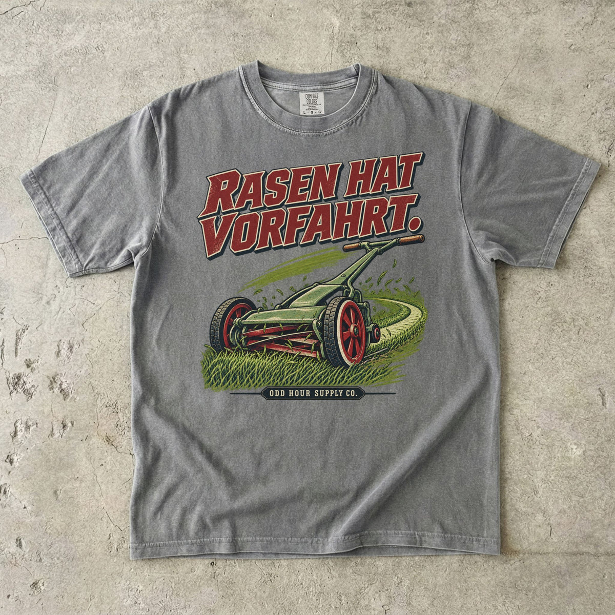 Comfort Colors 1717 T-Shirt in Granite: Grüner Handrasenmäher auf einer Rasenfläche, darüber RASEN HAT VORFAHRT. in Rot, darunter ODD HOUR SUPPLY CO.