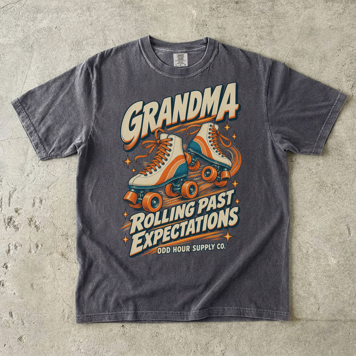 Comfort Colors 1717 T-Shirt in Pepper mit cremefarbenen Rollschuhen mit orangefarbenen und türkisen Details und Grandma Rolling Past Expectations-Schrift.