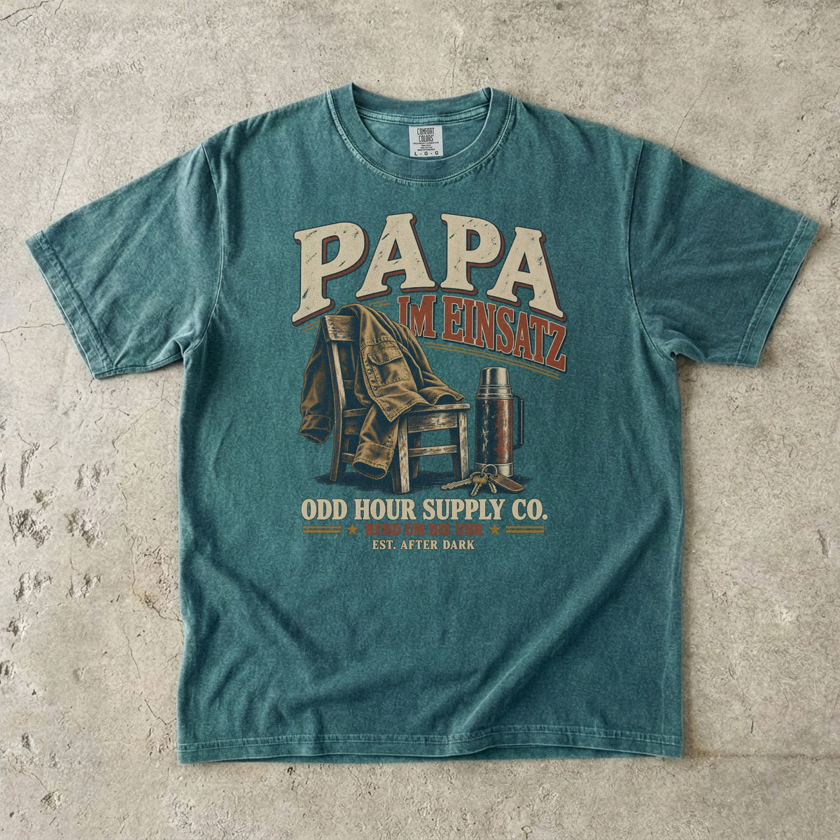 PAPA – Im Einsatz T-Shirt in Blue Spruce mit Arbeitsjacke über einem Stuhl und Thermoskanne im Vintage-Look, Vorderansicht