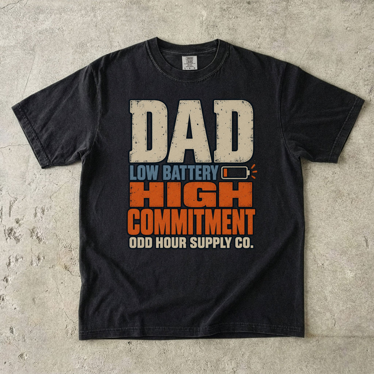 Comfort Colors 1717 T-Shirt in Black mit großer Dad Low Battery High Commitment-Schrift in Creme, Blau und Orange sowie fast leerem Batteriesymbol.