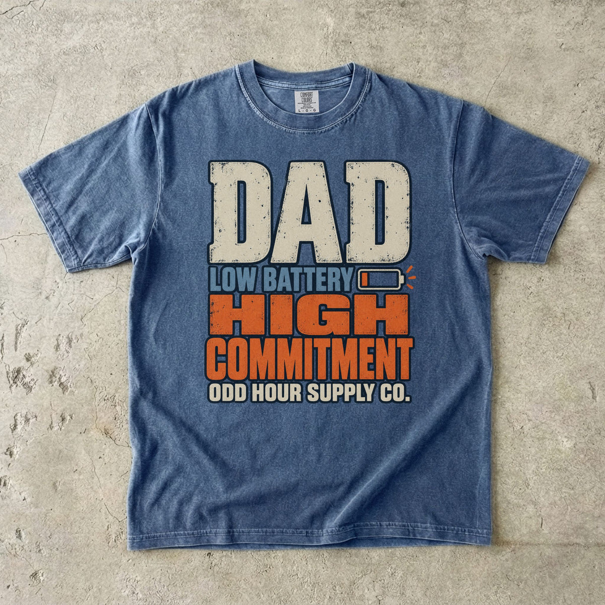 Comfort Colors 1717 T-Shirt in Denim mit großer Dad Low Battery High Commitment-Schrift in Creme, Blau und Orange sowie fast leerem Batteriesymbol.