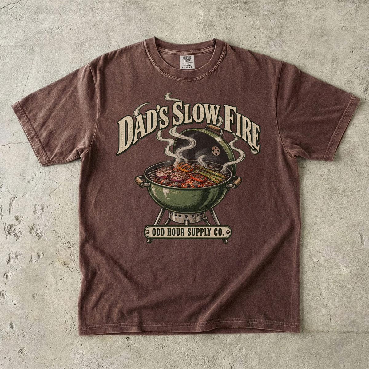 Comfort Colors 1717 T-Shirt in Espresso mit grünem Kugelgrill, Gemüse auf dem Rost, Rauchwolken und Dad’s Slow Fire-Schrift.