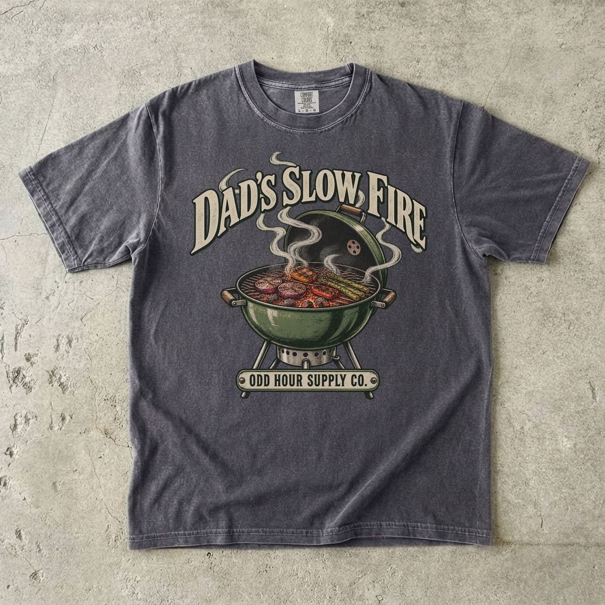 Comfort Colors 1717 T-Shirt in Pepper mit grünem Kugelgrill, Gemüse auf dem Rost, Rauchwolken und Dad’s Slow Fire-Schrift.