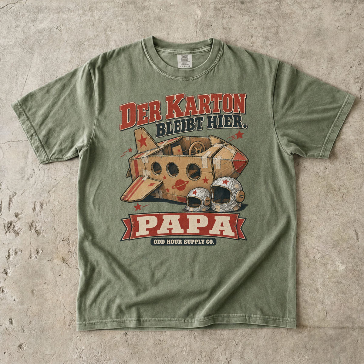 Comfort Colors 1717 T-Shirt in Hemp: Raumschiff aus braunen Kartons mit roten Sternen und zwei silbernen Helmen, dazu DER KARTON BLEIBT HIER., PAPA und ODD HOUR SUPPLY CO.