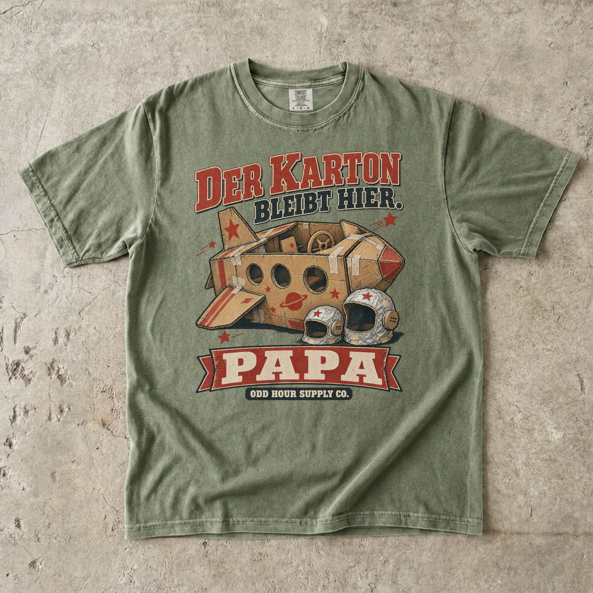 Comfort Colors 1717 T-Shirt in Hemp: Raumschiff aus braunen Kartons mit roten Sternen und zwei silbernen Helmen, dazu DER KARTON BLEIBT HIER., PAPA und ODD HOUR SUPPLY CO.