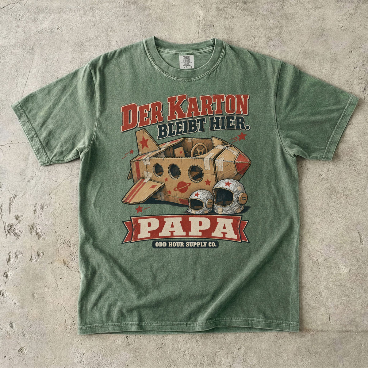 Comfort Colors 1717 T-Shirt in Moss: Raumschiff aus braunen Kartons mit roten Sternen und zwei silbernen Helmen, dazu DER KARTON BLEIBT HIER., PAPA und ODD HOUR SUPPLY CO.