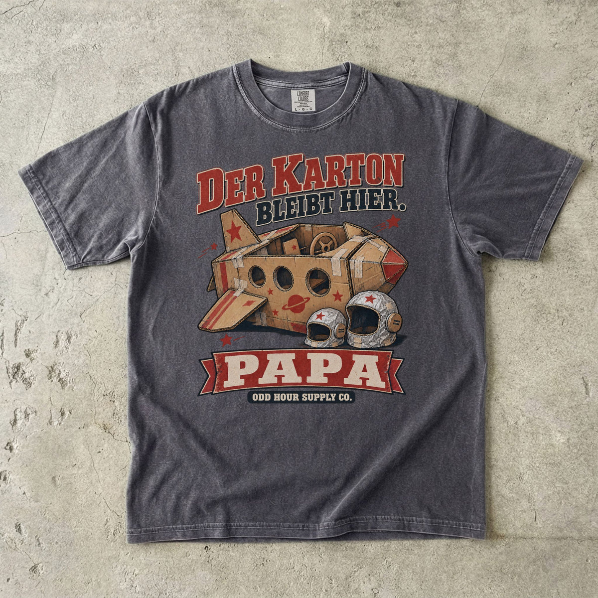 Comfort Colors 1717 T-Shirt in Pepper: Raumschiff aus braunen Kartons mit roten Sternen und zwei silbernen Helmen, dazu DER KARTON BLEIBT HIER., PAPA und ODD HOUR SUPPLY CO.