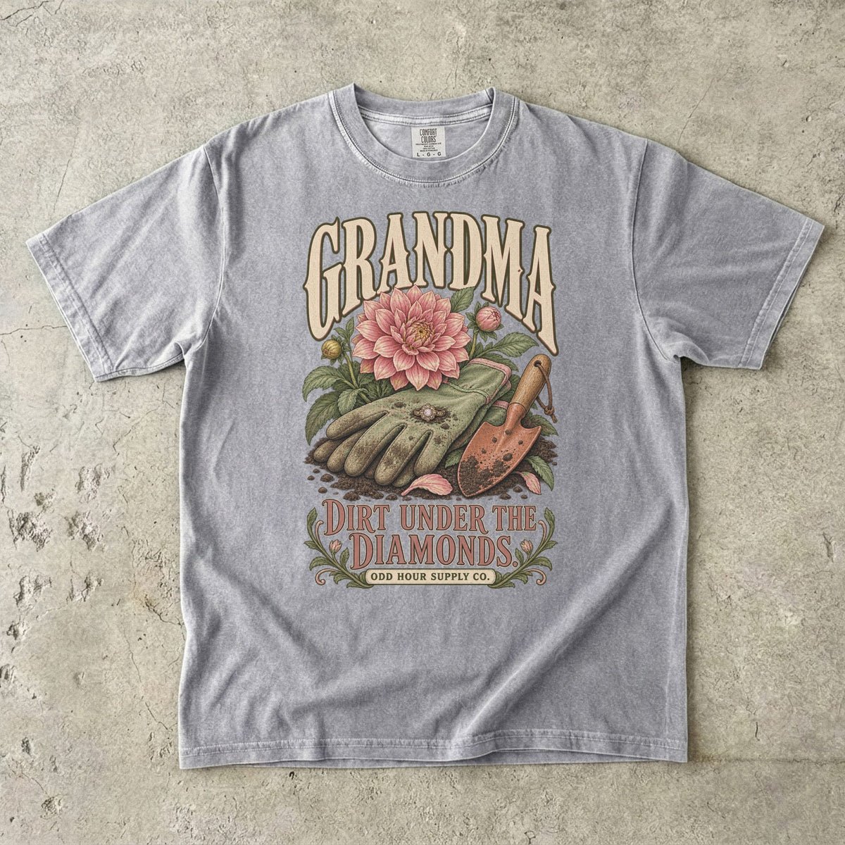 Comfort Colors 1717 T-Shirt in Grey mit Gartenhandschuhen, Ring, rosa Dahlie, Pflanzkelle und der Aufschrift Grandma Dirt Under the Diamonds.
