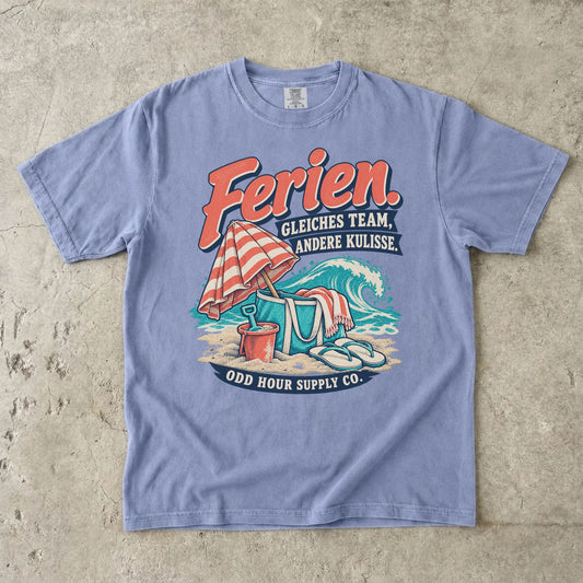 Comfort Colors 1717 T-Shirt in Ice Blue mit dem Motiv „Ferien. Gleiches Team, andere Kulisse“ mit Strandmotiv, Vorderansicht