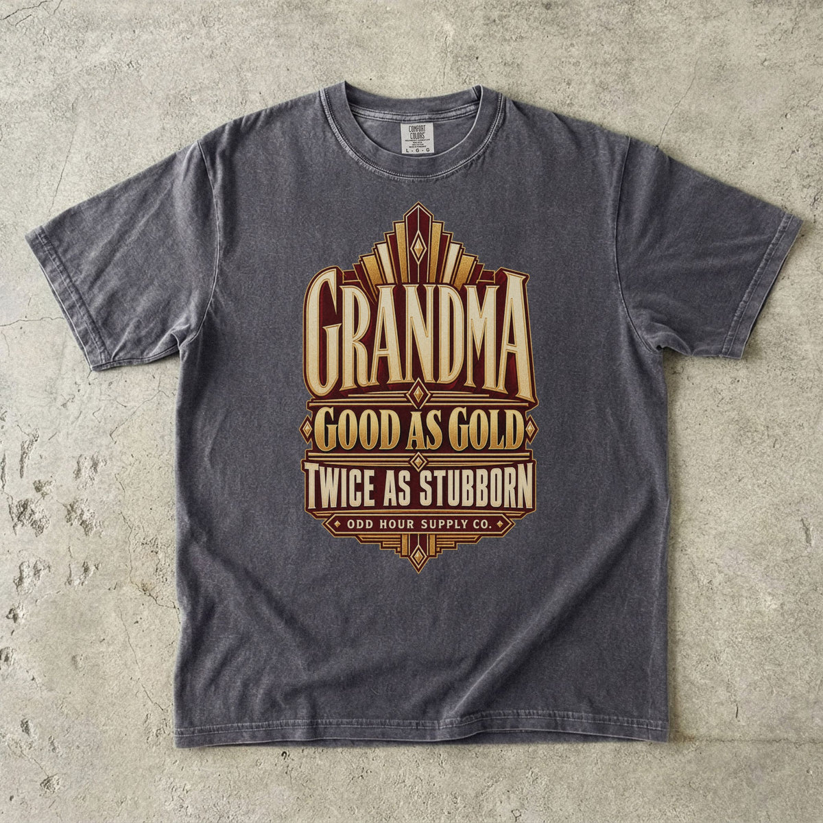 Comfort Colors 1717 T-Shirt in Pepper mit goldfarbenen geometrischen Linien und der Aufschrift Grandma Good as Gold Twice as Stubborn auf burgunderroter Fläche.