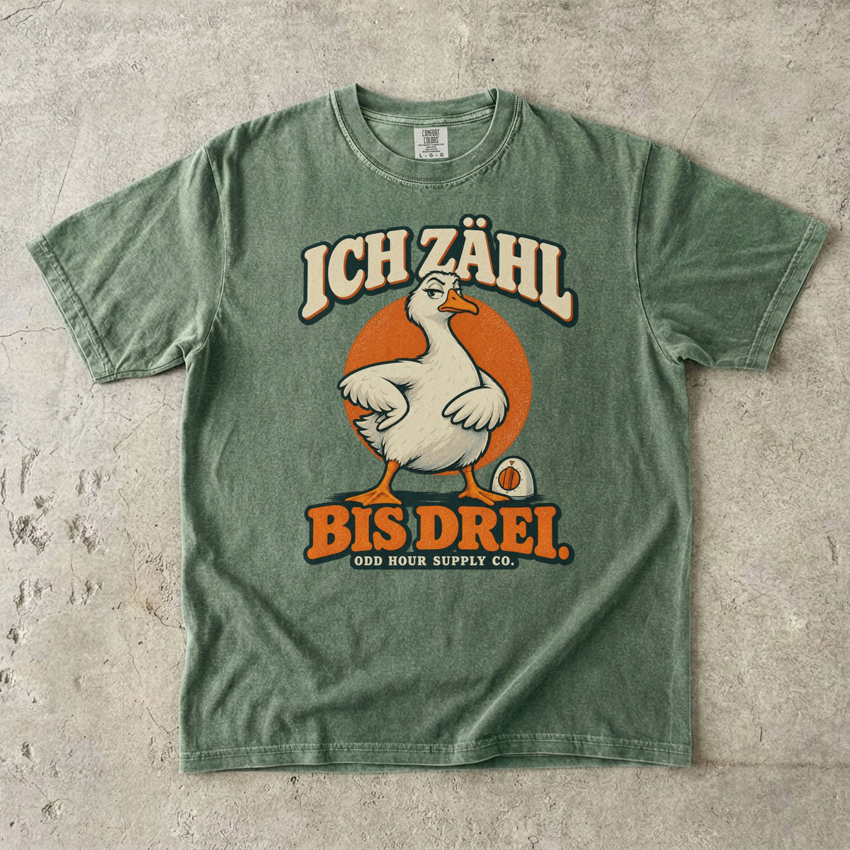 Comfort Colors 1717 T-Shirt in Moss mit dem Motiv „Ich zähl bis drei“ mit Gans, Vorderansicht