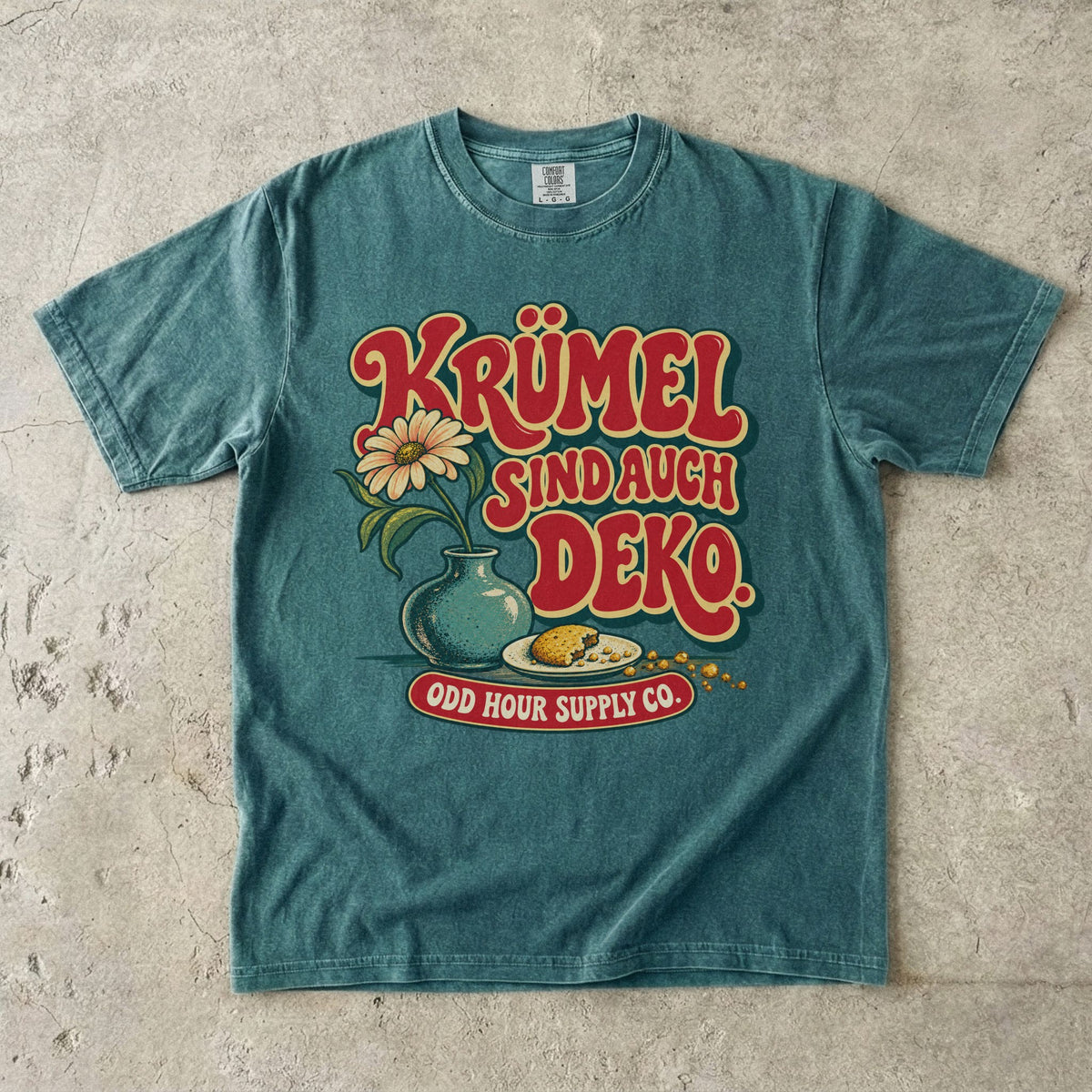 Comfort Colors 1717 T-Shirt in Blue Spruce mit dem Motiv „Krümel sind auch Deko“ mit Blumenvase, Vorderansicht