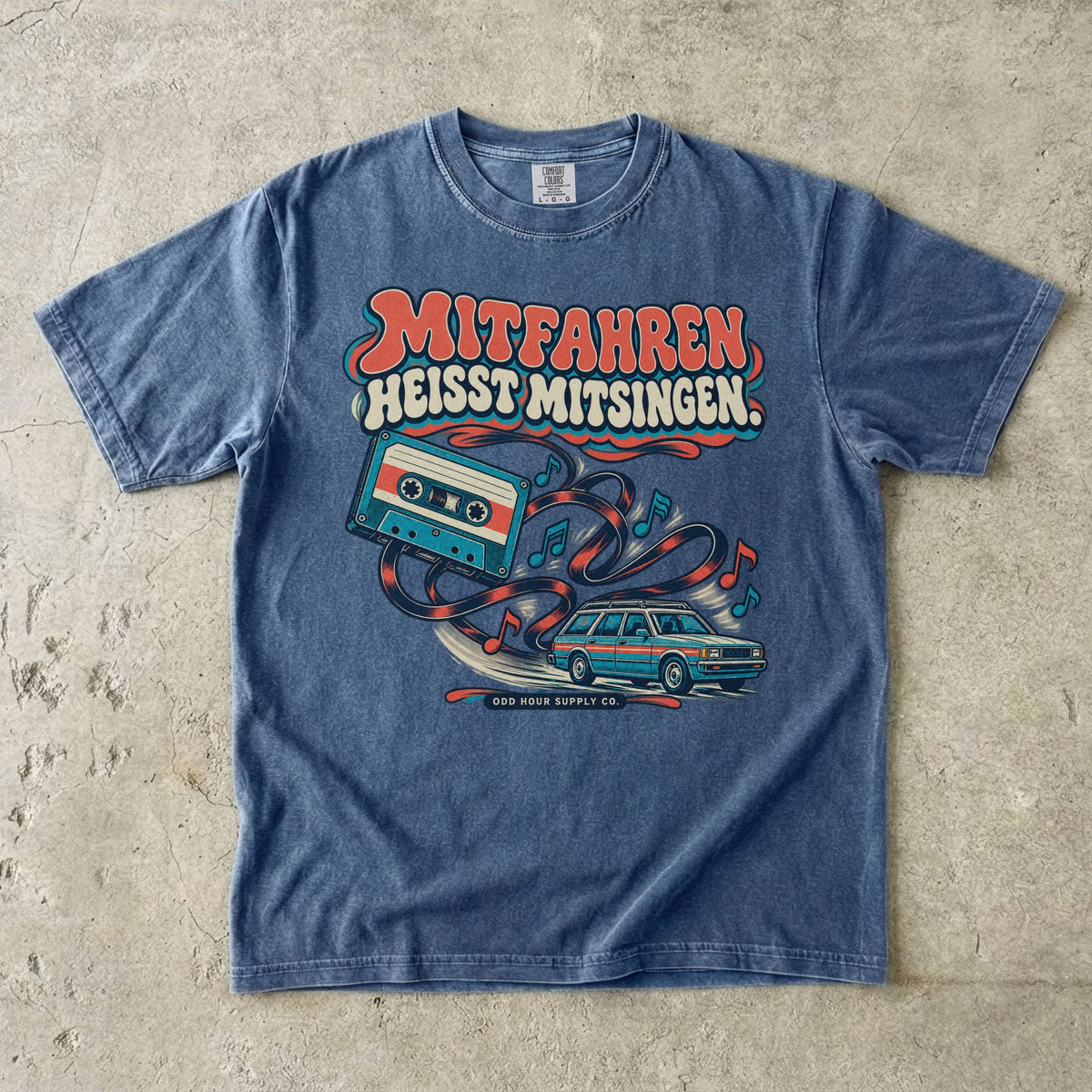 Comfort Colors 1717 T-Shirt in Denim: Türkise Musikkassette mit Band, Noten und Familienkombi, darüber MITFAHREN HEISST MITSINGEN., darunter ODD HOUR SUPPLY CO.