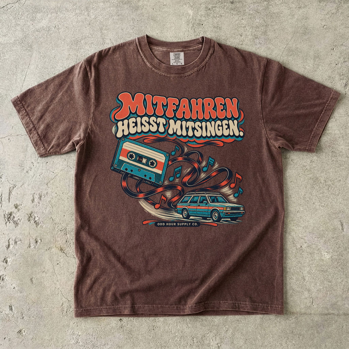 Comfort Colors 1717 T-Shirt in Espresso: Türkise Musikkassette mit Band, Noten und Familienkombi, darüber MITFAHREN HEISST MITSINGEN., darunter ODD HOUR SUPPLY CO.
