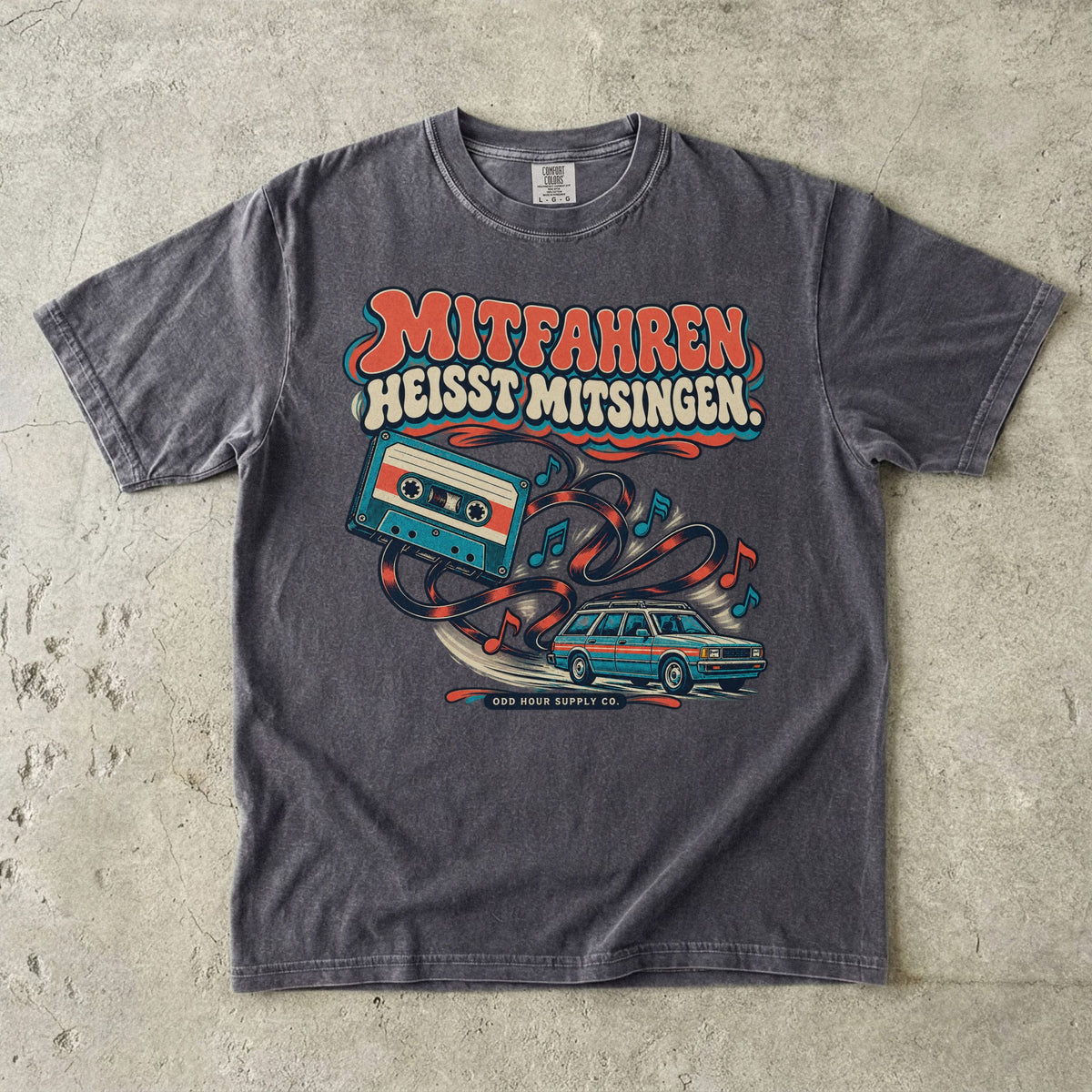 Comfort Colors 1717 T-Shirt in Pepper: Türkise Musikkassette mit Band, Noten und Familienkombi, darüber MITFAHREN HEISST MITSINGEN., darunter ODD HOUR SUPPLY CO.