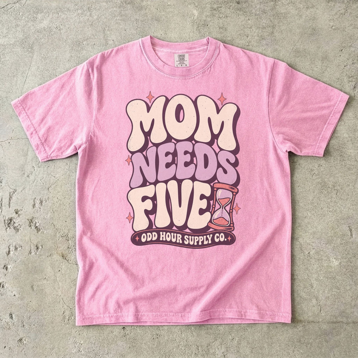 Comfort Colors 1717 T-Shirt in Blossom mit cremefarbener und fliederfarbener Mom Needs Five-Schrift, rosa Sternen und einer Sanduhr.