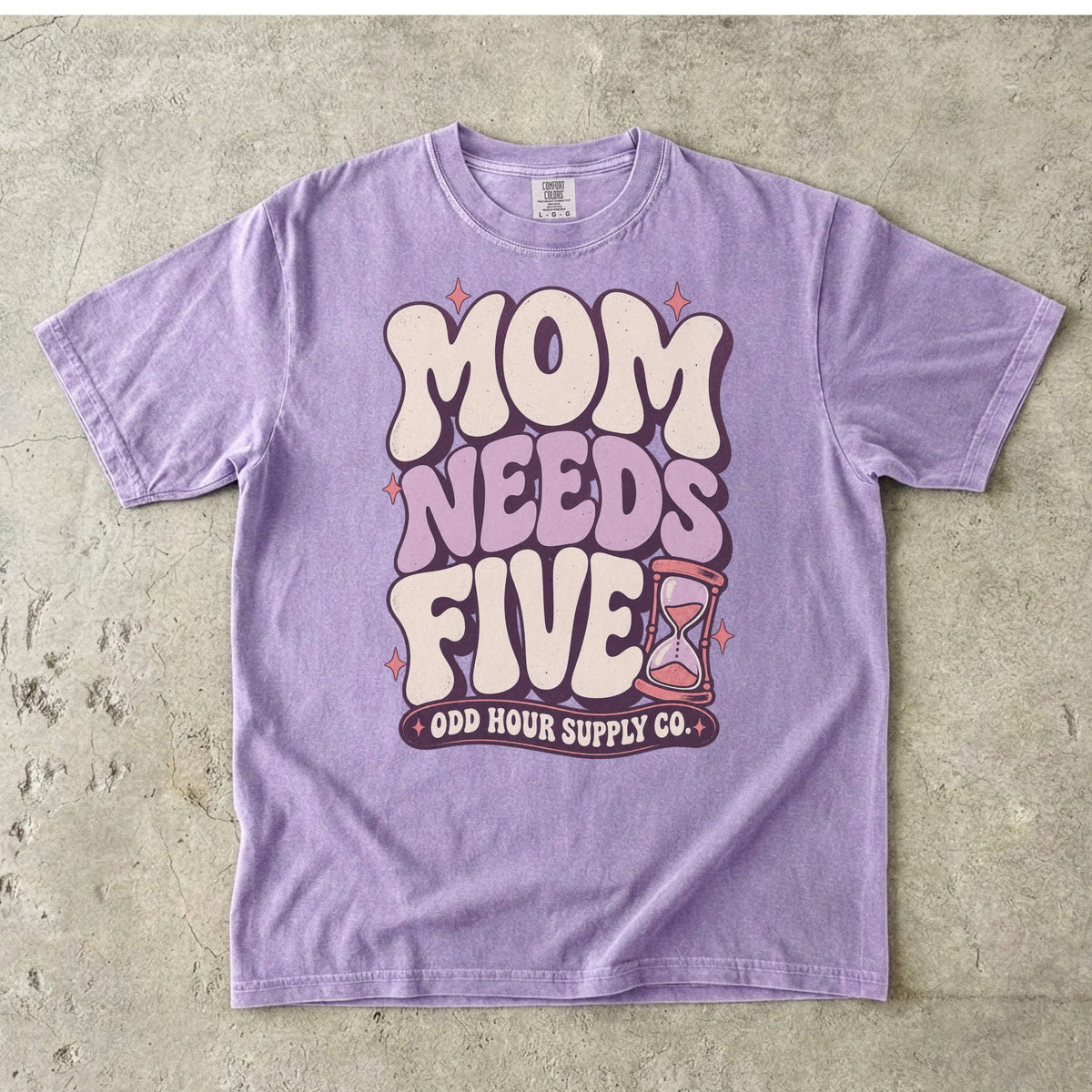 Comfort Colors 1717 T-Shirt in Orchid mit cremefarbener und fliederfarbener Mom Needs Five-Schrift, rosa Sternen und einer Sanduhr.