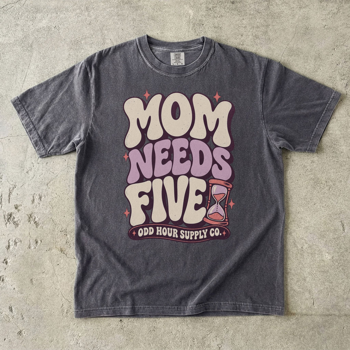 Comfort Colors 1717 T-Shirt in Pepper mit cremefarbener und fliederfarbener Mom Needs Five-Schrift, rosa Sternen und einer Sanduhr.