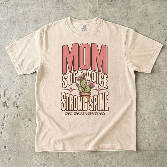 Comfort Colors 1717 T-Shirt in Ivory mit rosa Mom-Schrift, Soft Voice Strong Spine-Aufschrift und einem blühenden Kaktus im Terrakottatopf.