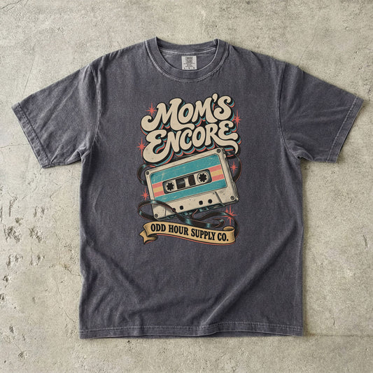 Comfort Colors 1717 T-Shirt in Pepper mit türkis-cremefarbener Musikkassette, losem Kassettenband, korallfarbenen Sternen und Mom’s Encore-Schrift.