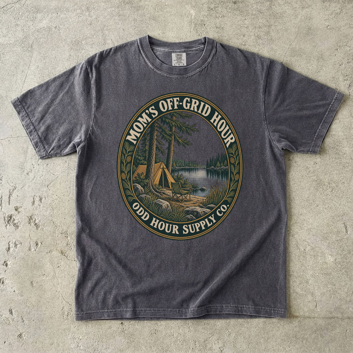 Comfort Colors 1717 T-Shirt in Pepper mit ovalem Mom’s Off-Grid Hour-Abzeichen, Zelt, Campingstuhl, Kiefern und See.