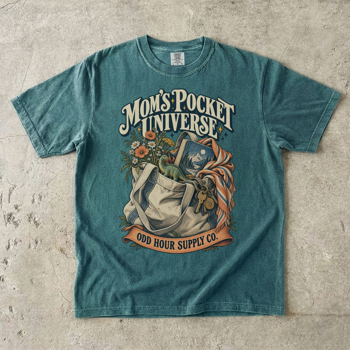 Comfort Colors 1717 T-Shirt in Blue Spruce mit gefüllter Stofftasche, Blumen, Buch, Spielzeugdinosaurier, Schlüsseln und Mom’s Pocket Universe-Schrift.