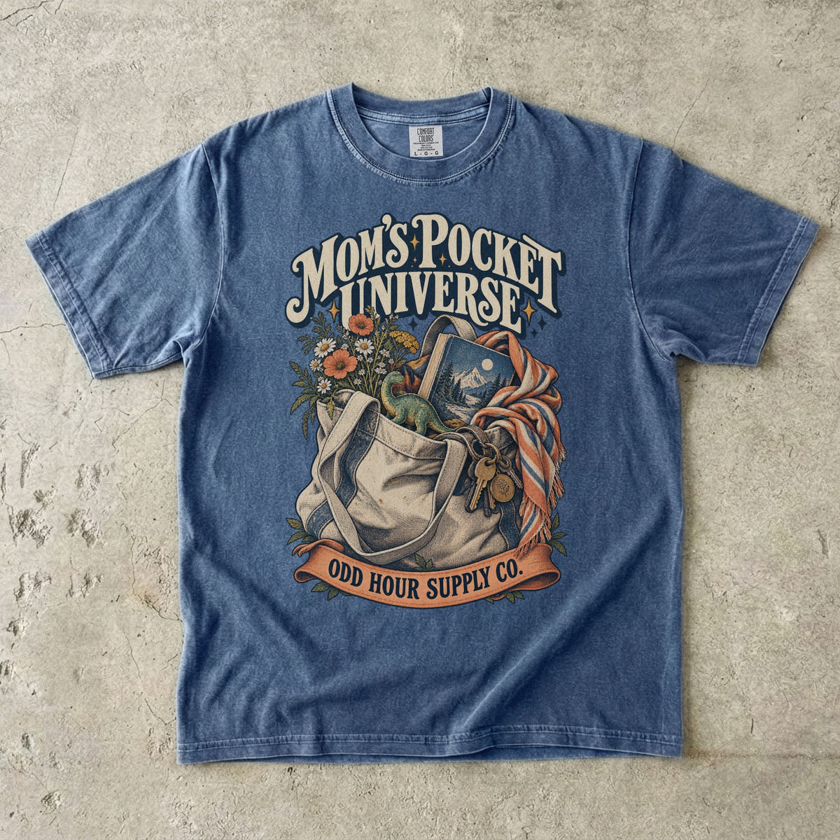 Comfort Colors 1717 T-Shirt in Denim mit gefüllter Stofftasche, Blumen, Buch, Spielzeugdinosaurier, Schlüsseln und Mom’s Pocket Universe-Schrift.