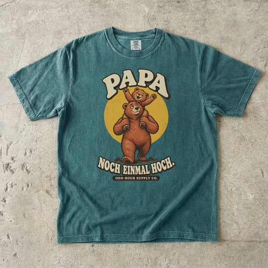 Comfort Colors 1717 T-Shirt in Blue Spruce: Großer Bär mit einem winkenden Bärenkind auf den Schultern vor einem gelben Kreis, dazu PAPA, NOCH EINMAL HOCH. und ODD HOUR SUPPLY CO.