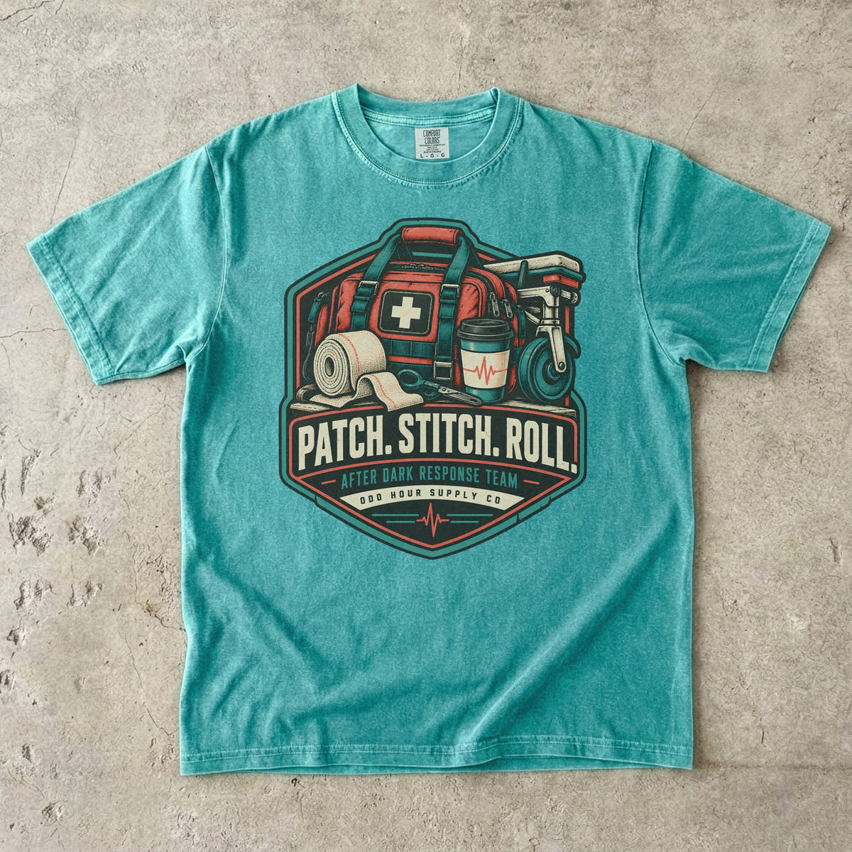 Comfort Colors 1717 T-Shirt in Seafoam mit Patch Stitch Roll Badge, korallfarbener Notfalltasche, Verbänden, Kaffeebecher und Petrol-Akzenten.