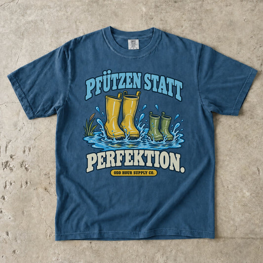 Comfort Colors 1717 T-Shirt in Midnight mit dem Motiv „Pfützen statt Perfektion“ mit Gummistiefeln, Vorderansicht