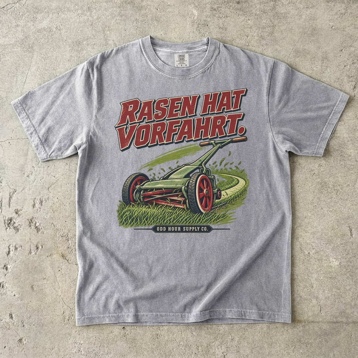 Comfort Colors 1717 T-Shirt in Grey: Grüner Handrasenmäher auf einer Rasenfläche, darüber RASEN HAT VORFAHRT. in Rot, darunter ODD HOUR SUPPLY CO.