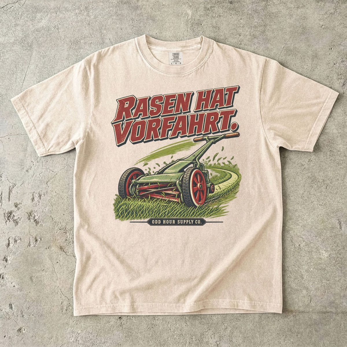 Comfort Colors 1717 T-Shirt in Ivory: Grüner Handrasenmäher auf einer Rasenfläche, darüber RASEN HAT VORFAHRT. in Rot, darunter ODD HOUR SUPPLY CO.
