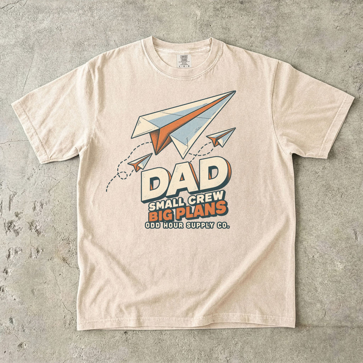 Comfort Colors 1717 T-Shirt in Ivory mit drei Papierfliegern, gestrichelten Flugbahnen und der Aufschrift Dad Small Crew Big Plans.