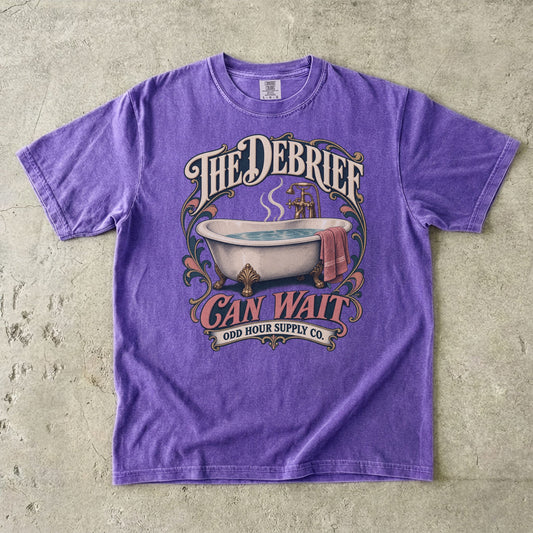 T-Shirt in Violet mit Vintage-Badewanne, THE DEBRIEF CAN WAIT und geschwungenem Odd Hour Supply Co. Branding.