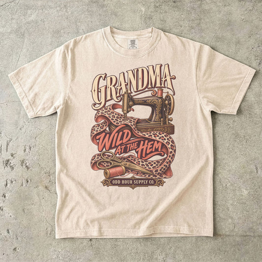 Comfort Colors 1717 T-Shirt in Ivory mit verzierter Nähmaschine, Stoff mit Leopardenmuster, Garnrollen und der Aufschrift Grandma Wild at the Hem.